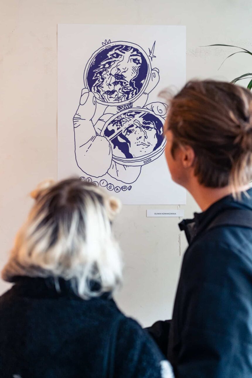 dwie osoby tyłem oglądają grafikę na ścianie