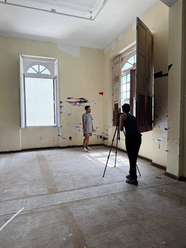 Stare puste wnętrze kobieta przy aparacie na statywie filmuje mężczyznę na dalszym planie