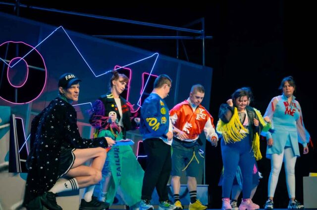 Grupa osób w kolorowych strojach na scenie