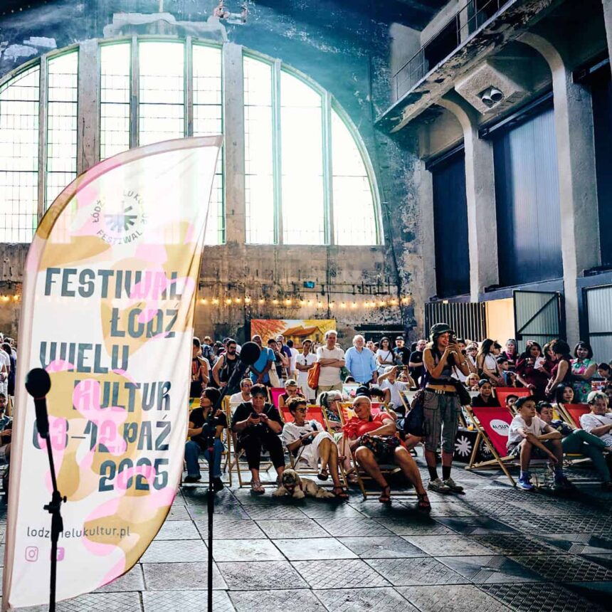 Wnętrze fabryki, w tle weseli ludzie, na pierwszym planie flaga reklamowa Festiwalu 2025