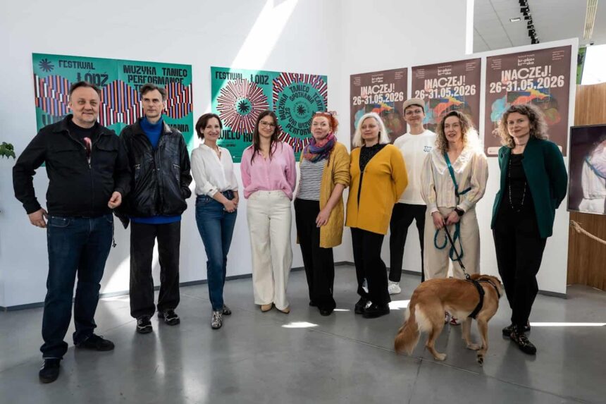 9 osób kobiet i mężczyzn oraz pies stoją na tle ścian z plakatami Festiwali