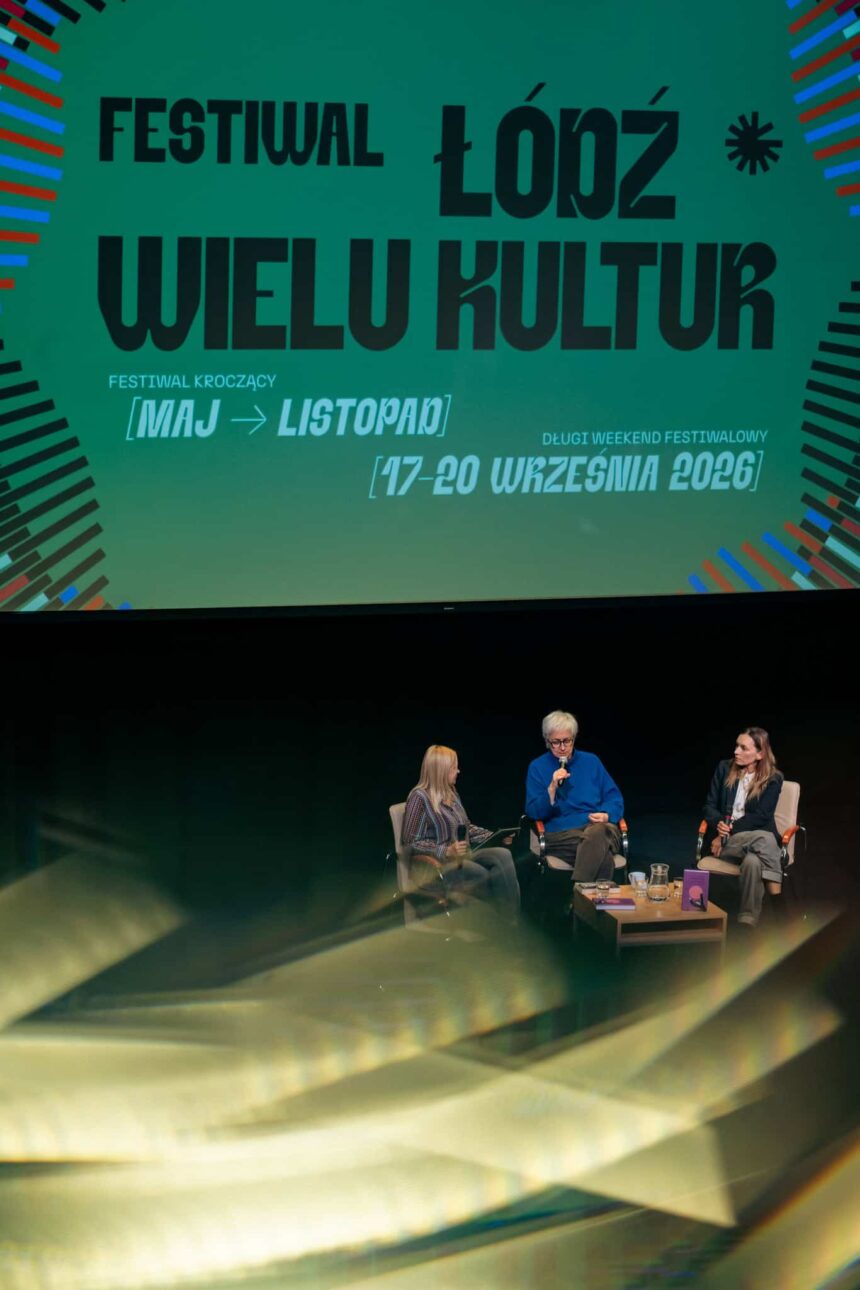 w oddali 3 osoby siedzą na krzesłach na scenie, w tle baner z napisem Festiwal Łódź Wielu Kultur. Na pierwszym tle świetliste maziaje