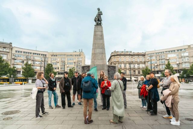 Grupa osób stoi na placu pod pomnikiem Tadeusza Kościuszki