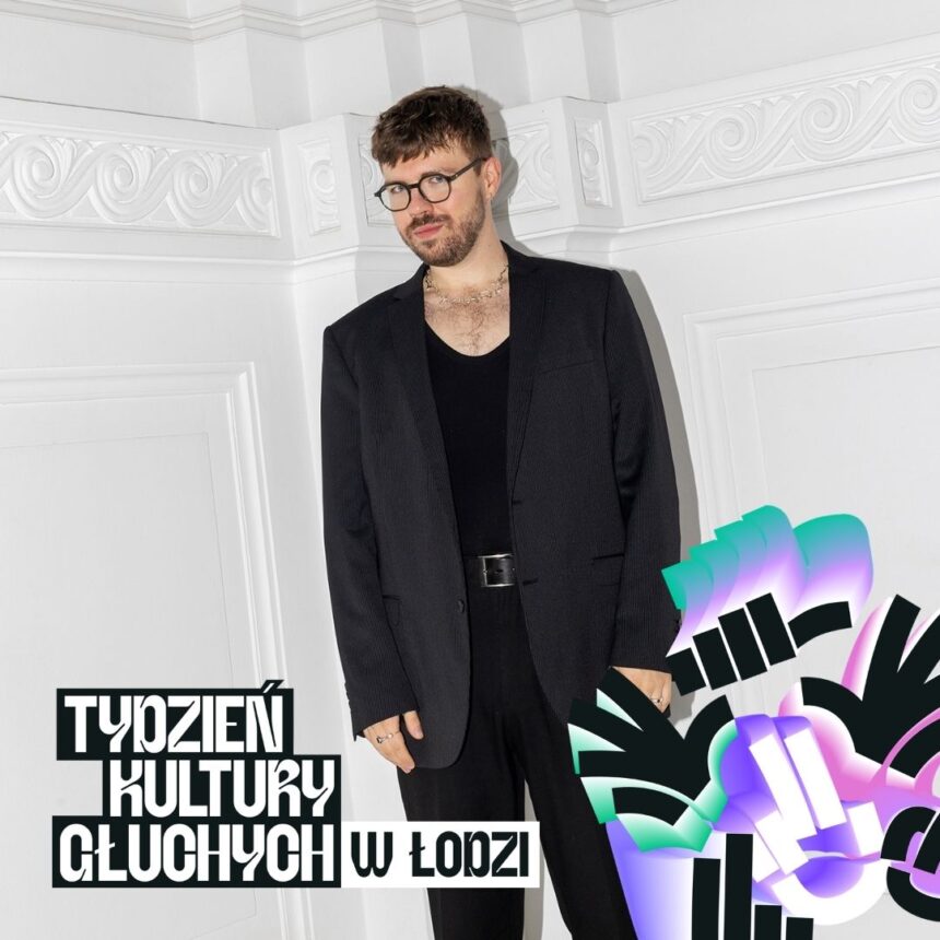 Mody męzczyzna w garniturze na tle białej ściany ze sztukaterią