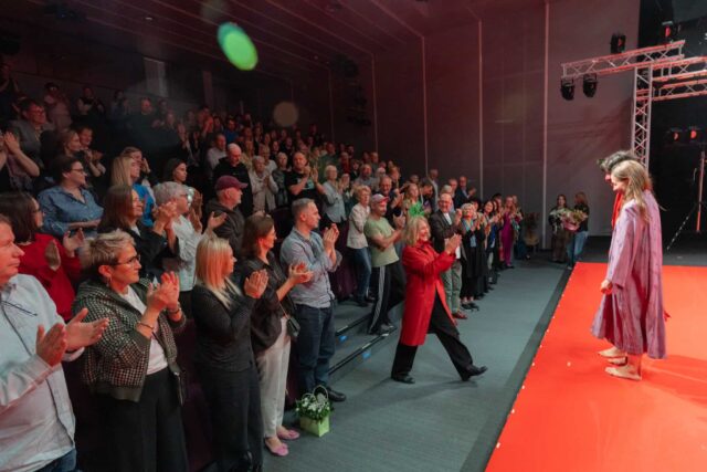 Publiczność stoi i klaszcze na sali teatralnej