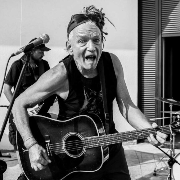 czarno-białe zdjęcie mężczyzny z gitarą przy mikrofonie
