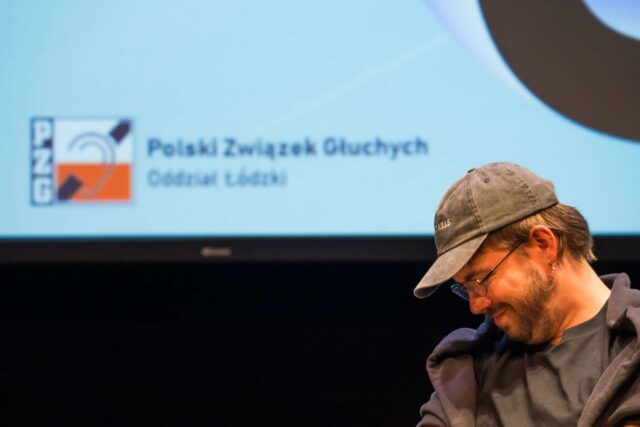 Profil mężczyzny w czapce, w tle logo PZG Łódź